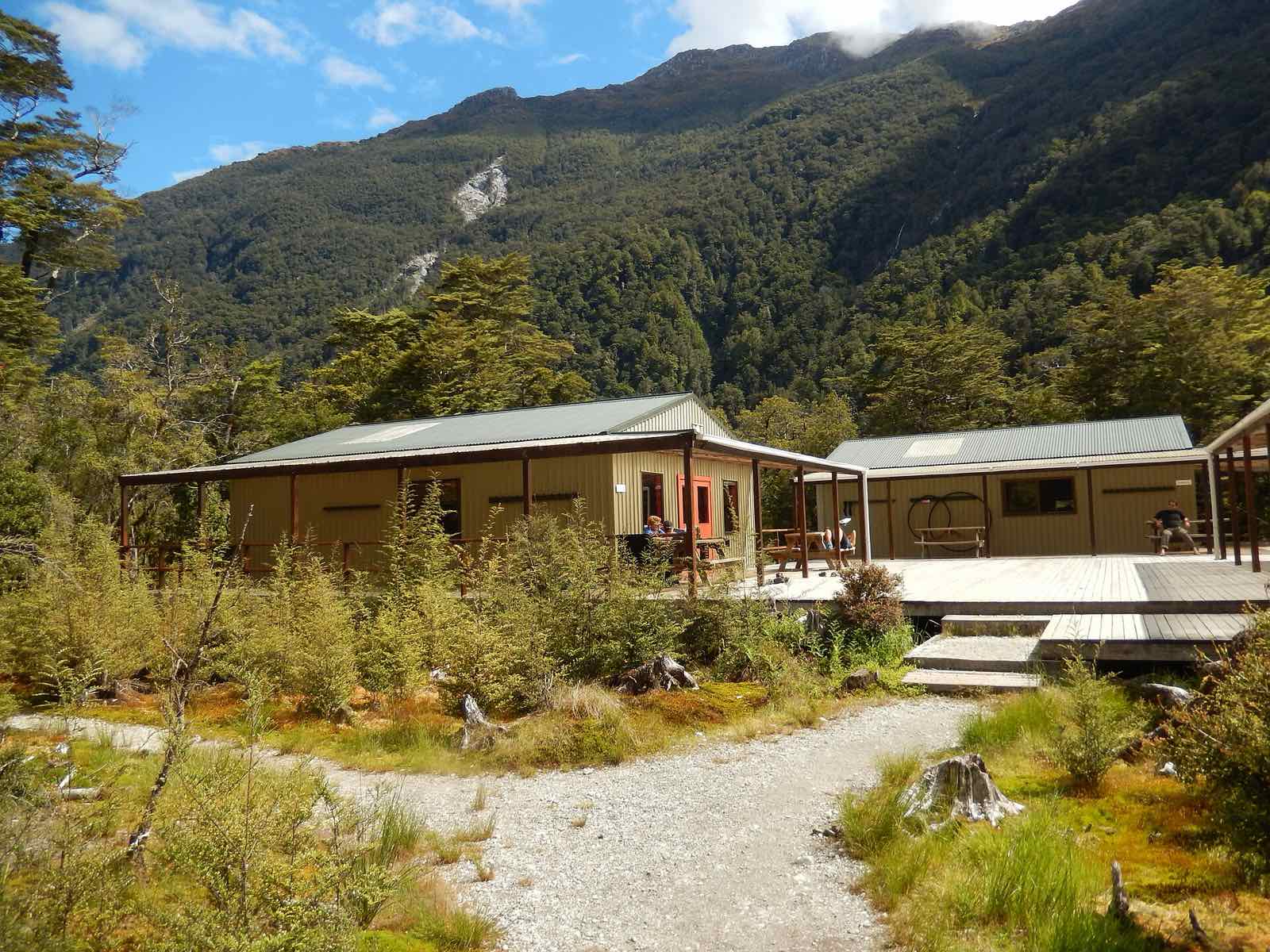 Clinton Hut, a low wooden building with a deck, at the edge of the forest