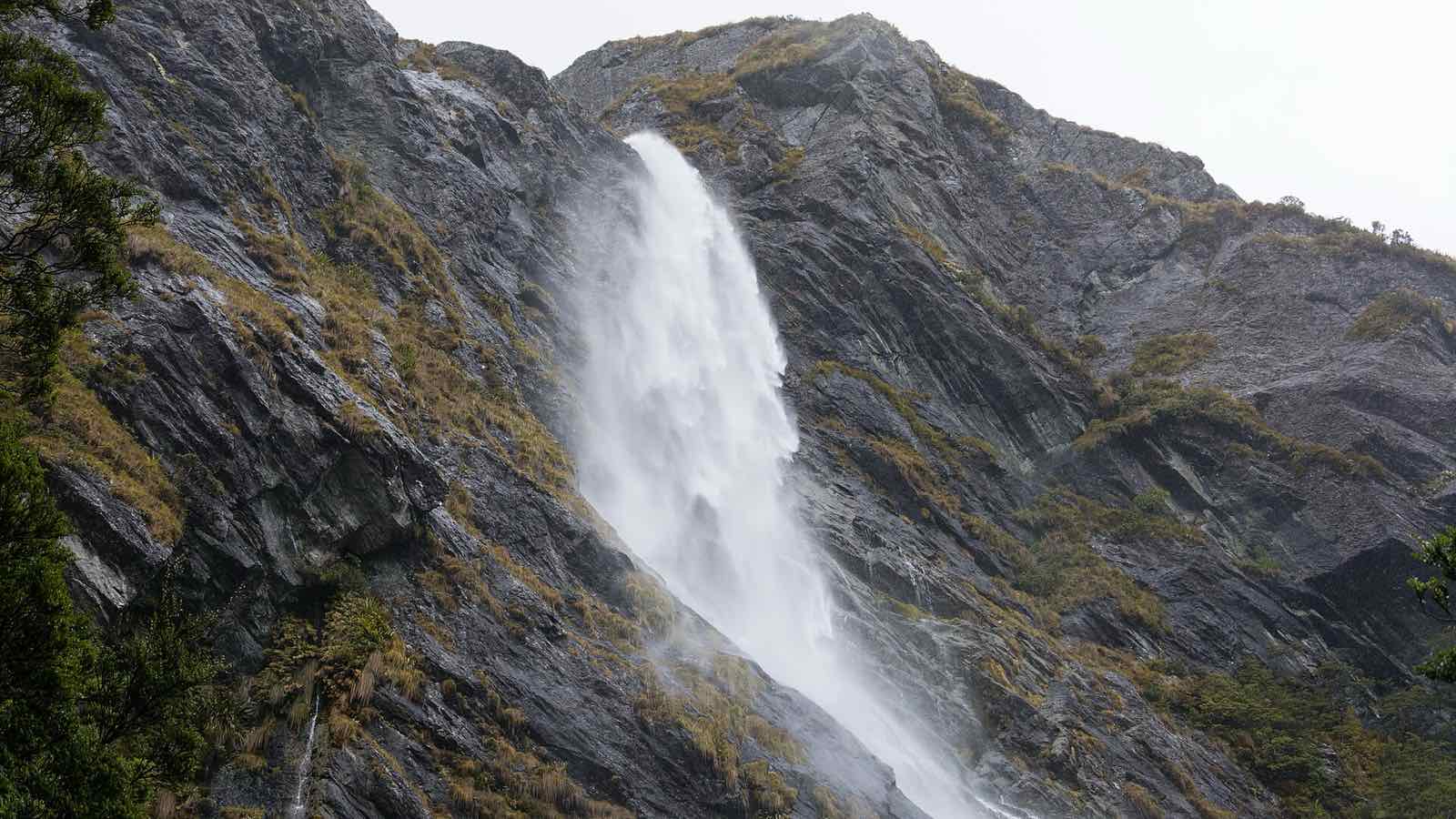 A tall waterfall pouring down a dark rock face