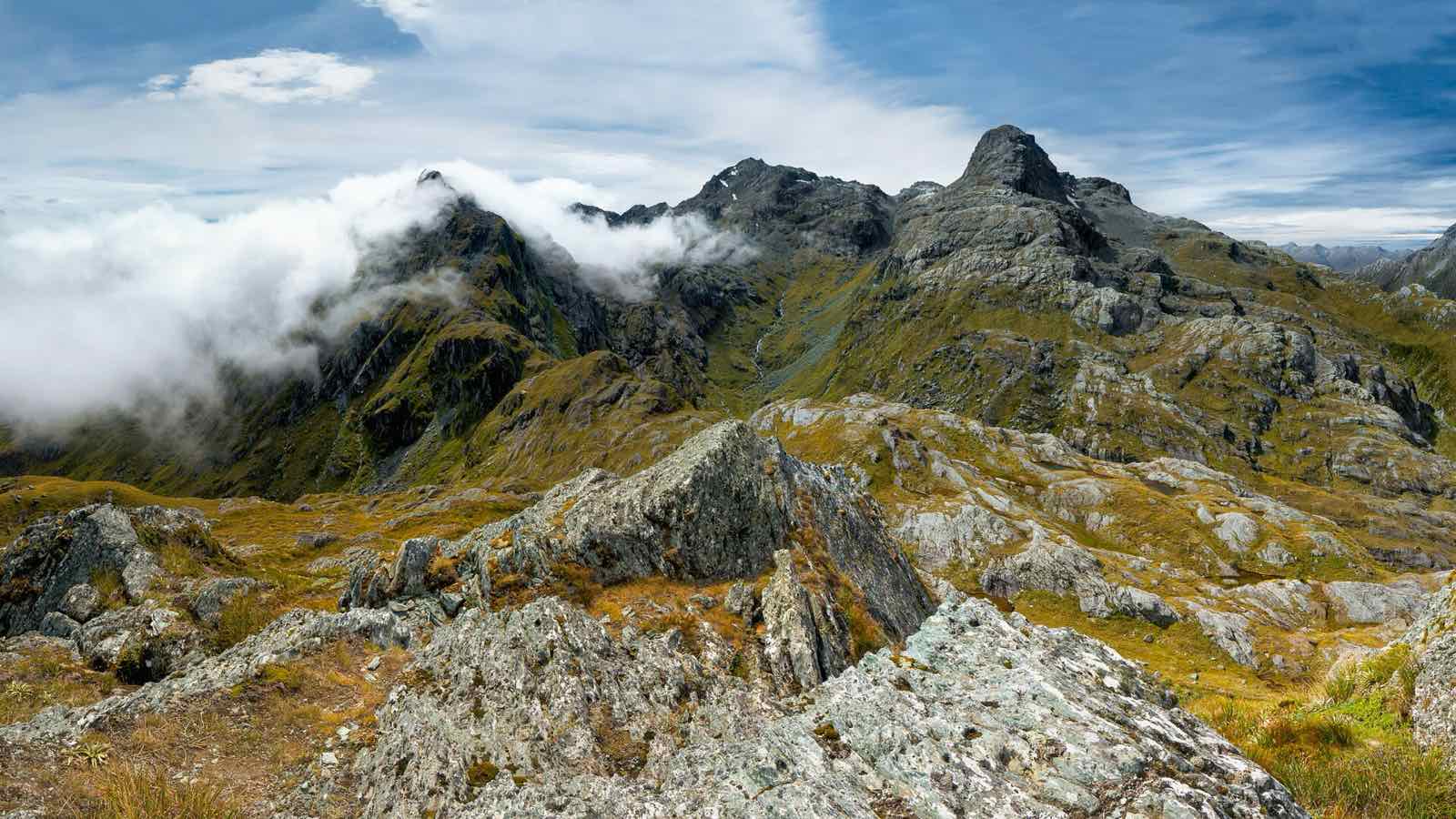 Rocky alpine ridge with cloud drifting over jagged peaks