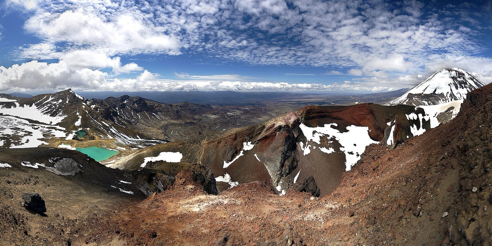 The turquoise Emerald Lakes below the red rim of Red Crater, with snow-capped Mount Ngauruhoe behind